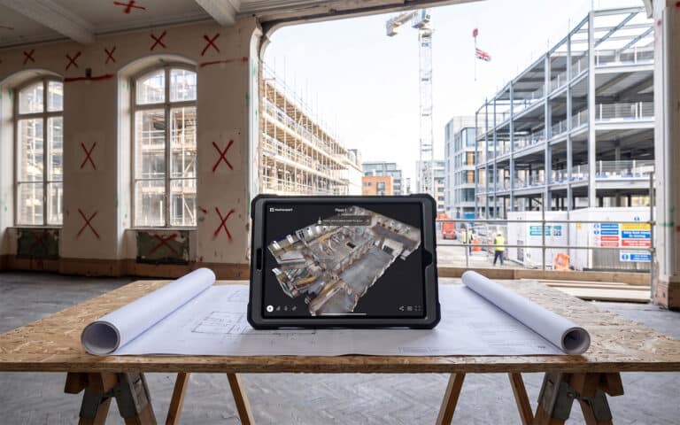 A rugged iPad on a UK construction site displaying a highly accurate 3D point cloud scan, representing enterprise construction virtual tours and BIM data capture.